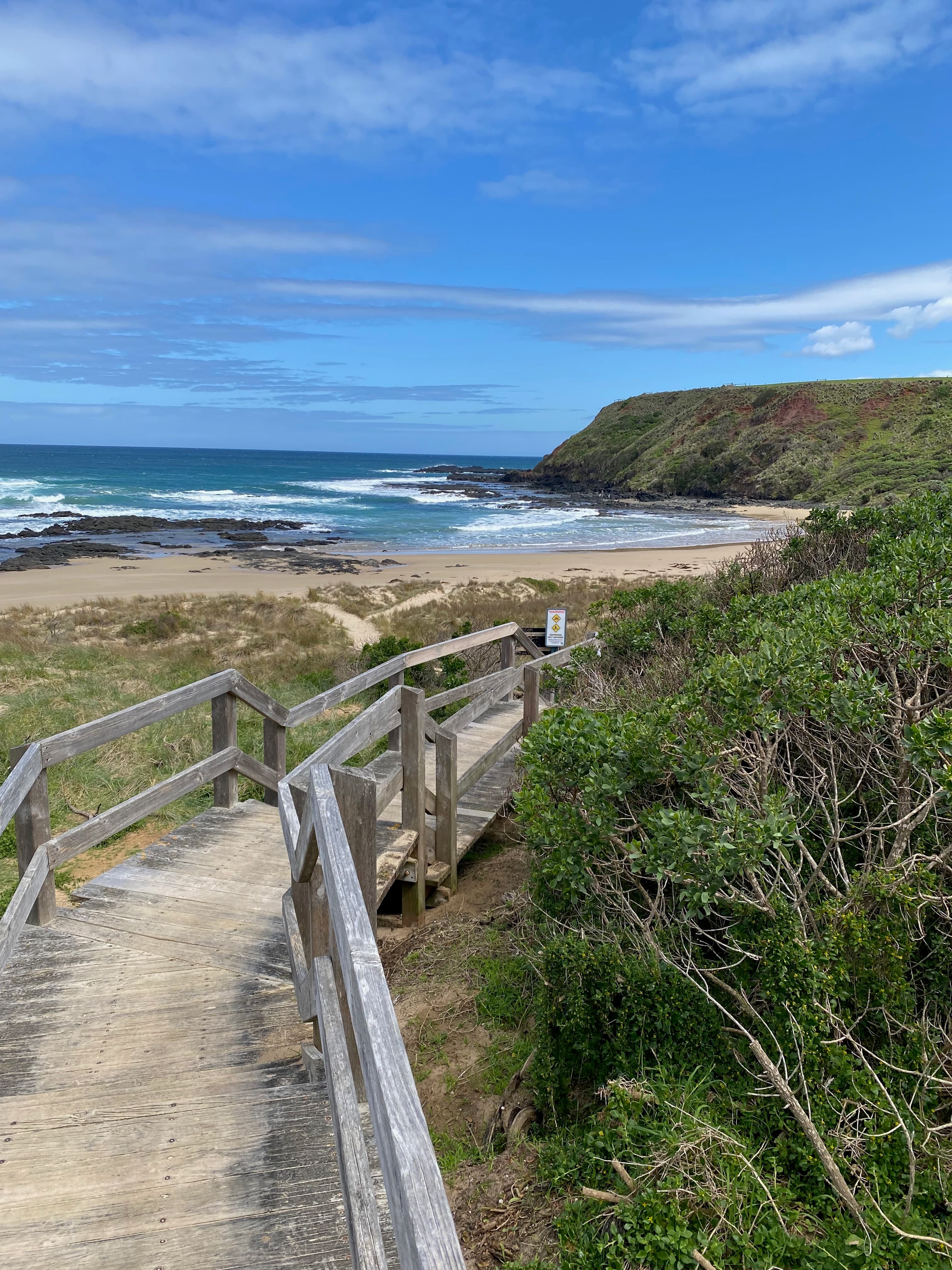 Wooden boardwalk leading down to a coastal beach cove