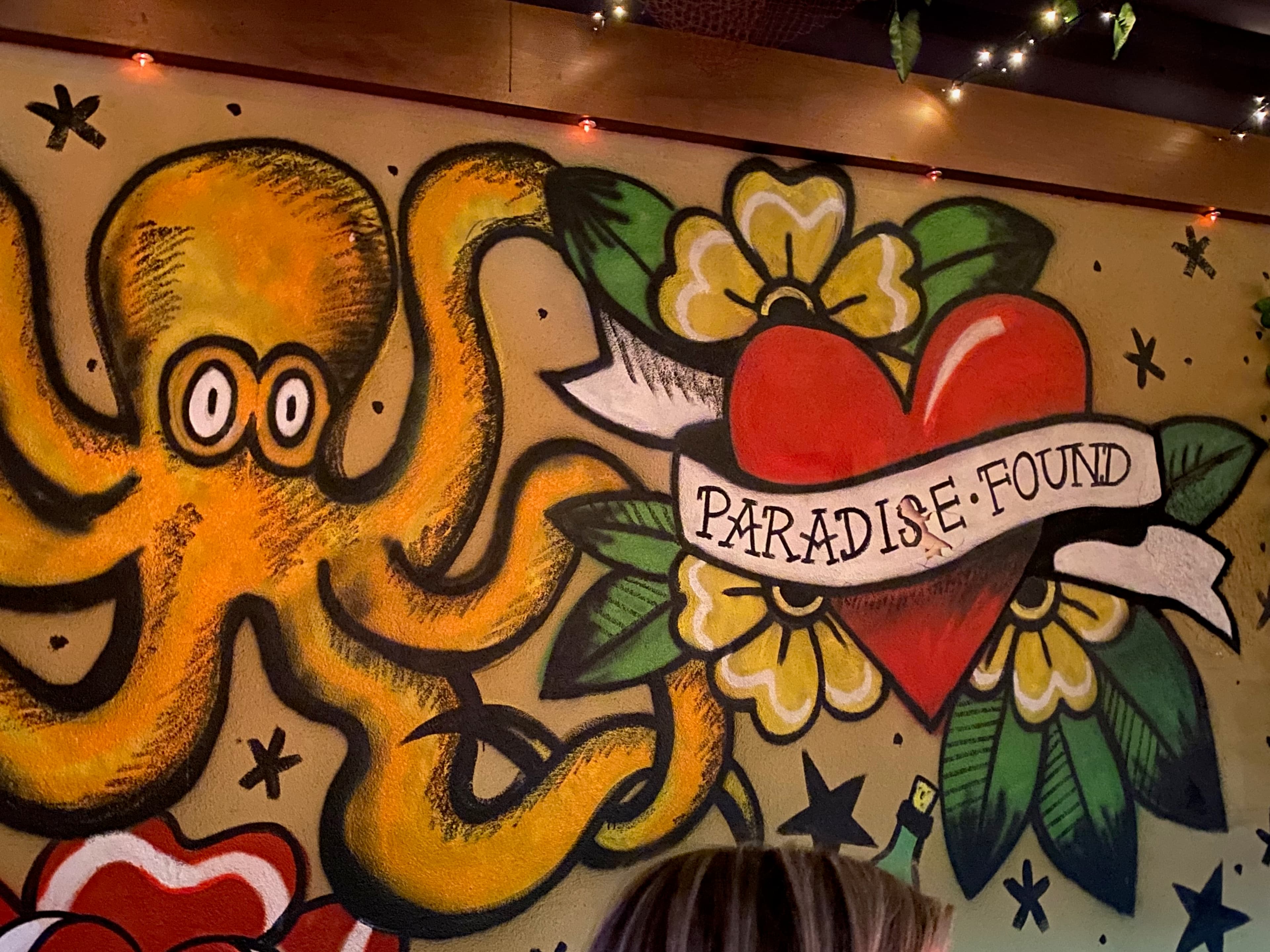 Tattoo-style mural reading Paradise Found inside a bar